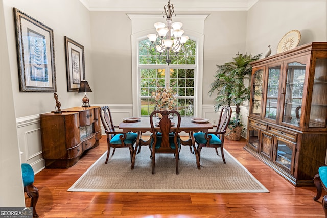 dining space with hardwood / wood-style floors, a chandelier, and ornamental molding