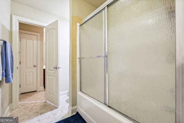 bathroom with bath / shower combo with glass door and tile patterned flooring