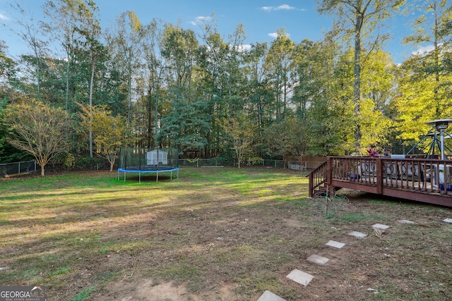 view of yard featuring a trampoline and a deck