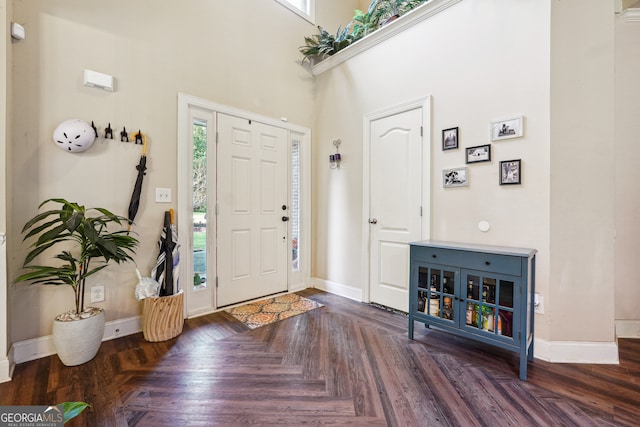 foyer featuring a wealth of natural light, dark parquet flooring, and a towering ceiling