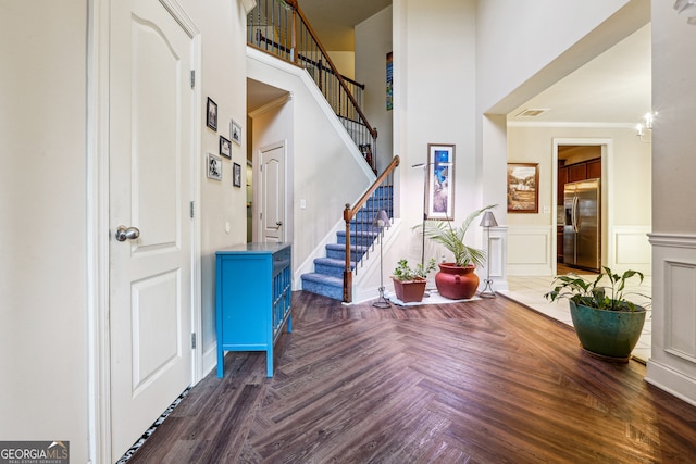 entryway with ornamental molding and a towering ceiling