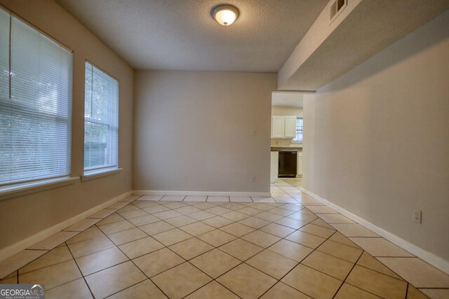 spare room featuring a textured ceiling and light tile patterned floors