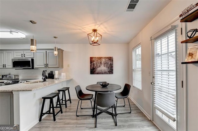 dining area featuring an inviting chandelier, sink, and light hardwood / wood-style flooring