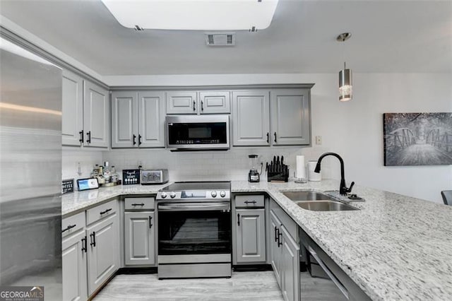 kitchen with sink, appliances with stainless steel finishes, hanging light fixtures, gray cabinetry, and decorative backsplash