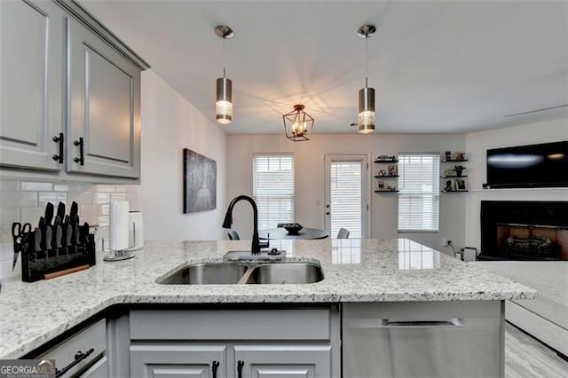 kitchen with hanging light fixtures, light stone countertops, gray cabinetry, and sink