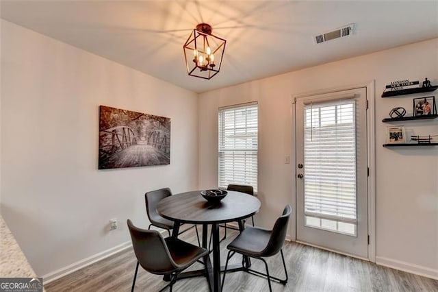 dining space with hardwood / wood-style floors and a chandelier