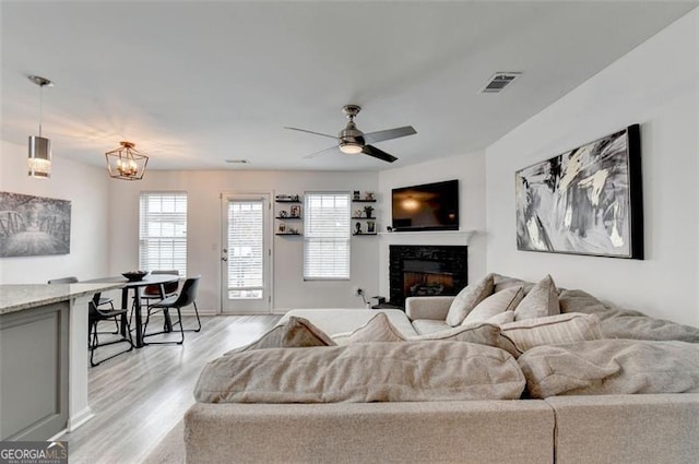 living room featuring ceiling fan with notable chandelier and light hardwood / wood-style flooring