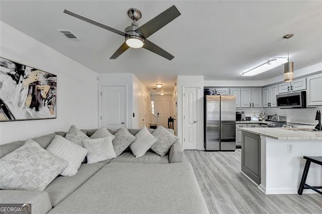 living room featuring light hardwood / wood-style flooring, ceiling fan, and sink