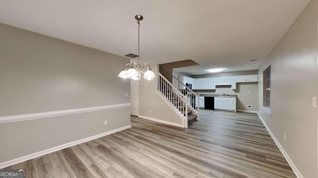 unfurnished dining area with light wood-type flooring, sink, and an inviting chandelier