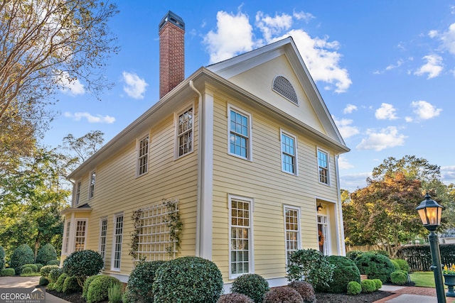 view of side of home with fence and a chimney