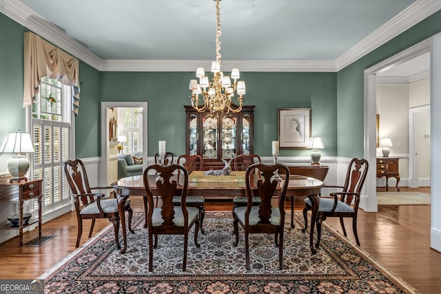 dining space with an inviting chandelier, ornamental molding, and hardwood / wood-style floors