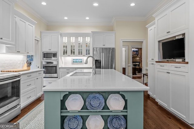 kitchen with white cabinetry, stainless steel appliances, sink, and an island with sink