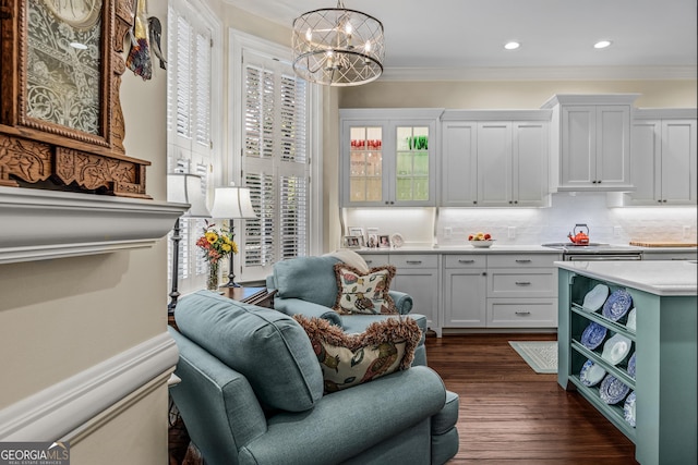 living area featuring dark hardwood / wood-style flooring, ornamental molding, and a chandelier