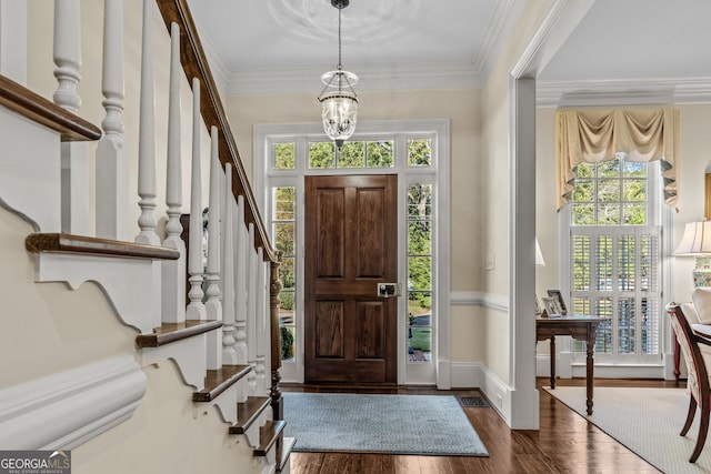 entrance foyer featuring dark wood-style floors, an inviting chandelier, ornamental molding, and stairway