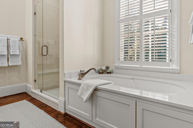 bathroom with hardwood / wood-style flooring and shower with separate bathtub