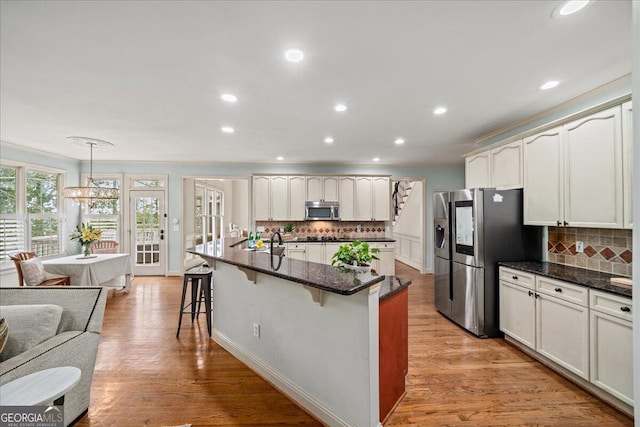 kitchen featuring light hardwood / wood-style flooring, tasteful backsplash, pendant lighting, and stainless steel appliances