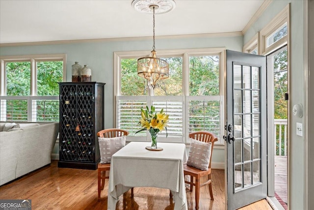 dining space featuring ornamental molding, an inviting chandelier, a healthy amount of sunlight, and light hardwood / wood-style flooring