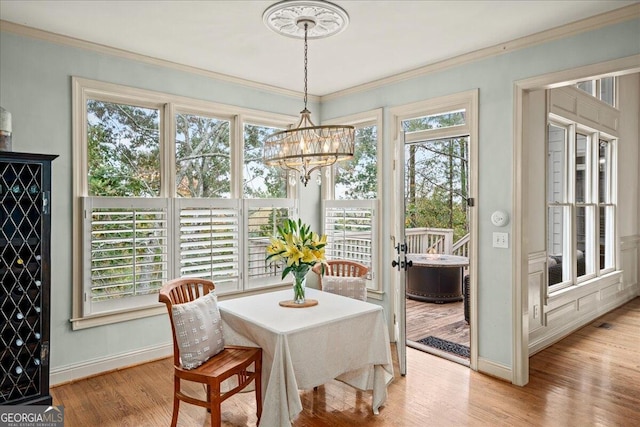 dining area featuring light wood-type flooring, a chandelier, and crown molding