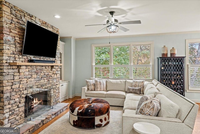 living room featuring a fireplace, light hardwood / wood-style floors, ceiling fan, and crown molding