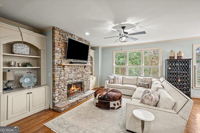 living room featuring ornamental molding, a fireplace, light hardwood / wood-style floors, and ceiling fan