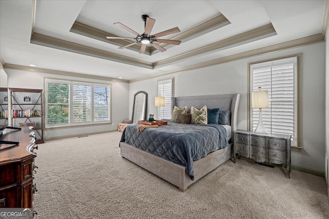 carpeted bedroom with ornamental molding, a tray ceiling, and ceiling fan