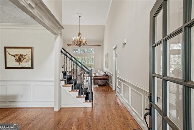 foyer entrance with an inviting chandelier, hardwood / wood-style floors, and ornamental molding