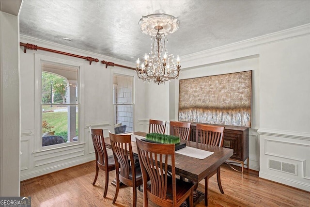 dining area with wood-type flooring, a chandelier, and crown molding