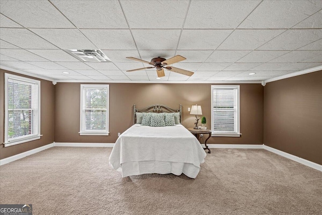 carpeted bedroom with a drop ceiling, ceiling fan, and crown molding