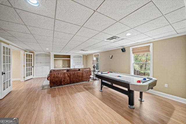 game room with built in shelves, a paneled ceiling, light hardwood / wood-style flooring, and french doors