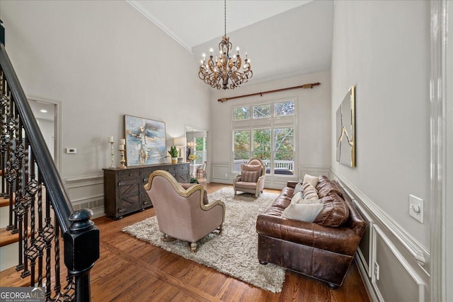 living room with a chandelier, dark hardwood / wood-style floors, high vaulted ceiling, and ornamental molding