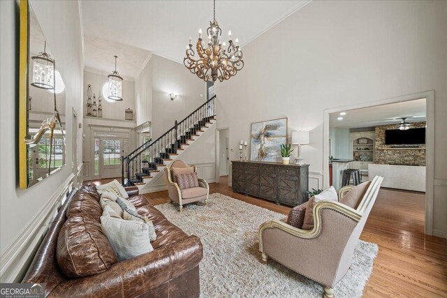 living room featuring a fireplace, light hardwood / wood-style floors, a high ceiling, and crown molding