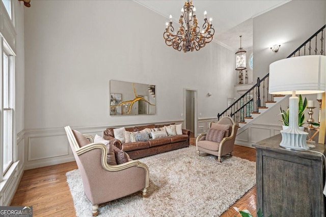 living room featuring a high ceiling, a wealth of natural light, light hardwood / wood-style floors, and crown molding