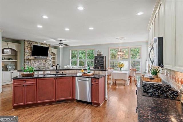 kitchen with sink, light wood-type flooring, appliances with stainless steel finishes, and decorative light fixtures