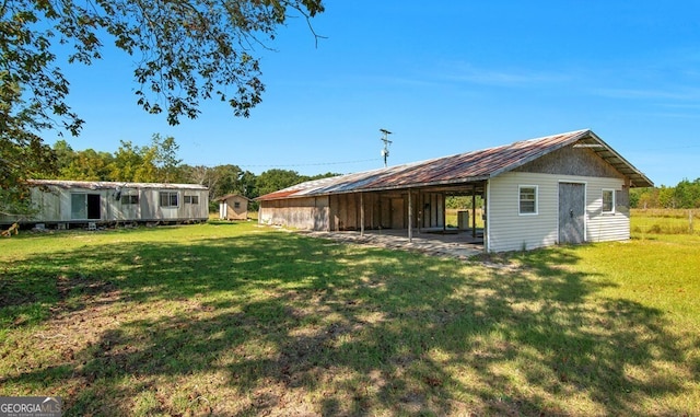 rear view of house with an outdoor structure, a lawn, and a patio area