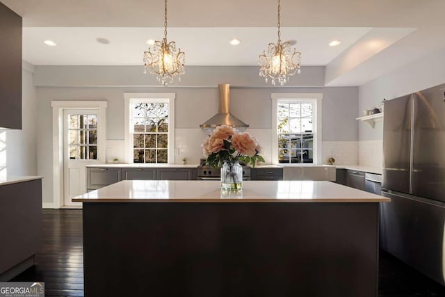 kitchen featuring stainless steel refrigerator, wall chimney exhaust hood, backsplash, a kitchen island, and dark wood-type flooring