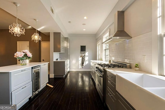 kitchen featuring high end range, wall chimney exhaust hood, plenty of natural light, gray cabinets, and wine cooler