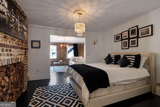 bedroom with dark wood-type flooring, a chandelier, ornamental molding, and brick wall