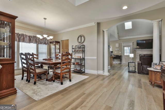 dining room with ornate columns, light hardwood / wood-style floors, crown molding, and an inviting chandelier