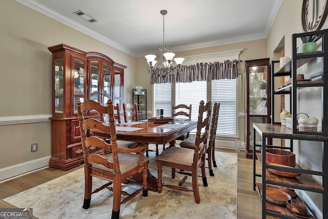 dining area with light wood-type flooring, a chandelier, and crown molding