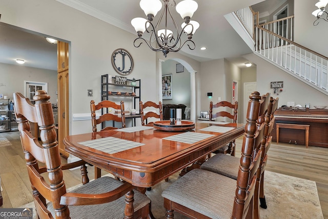 dining area featuring light hardwood / wood-style flooring, a chandelier, crown molding, and decorative columns