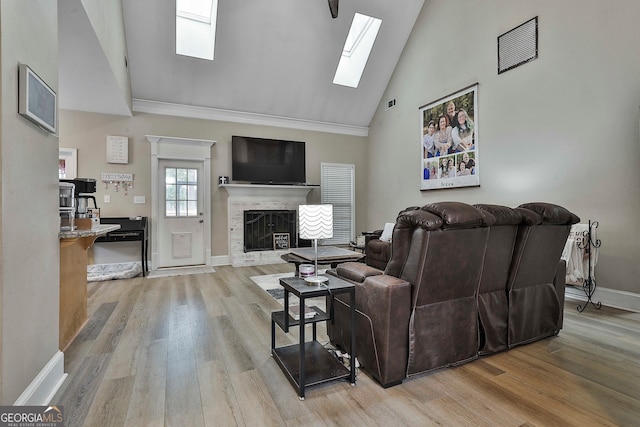 living room with high vaulted ceiling, light wood-type flooring, a skylight, and crown molding