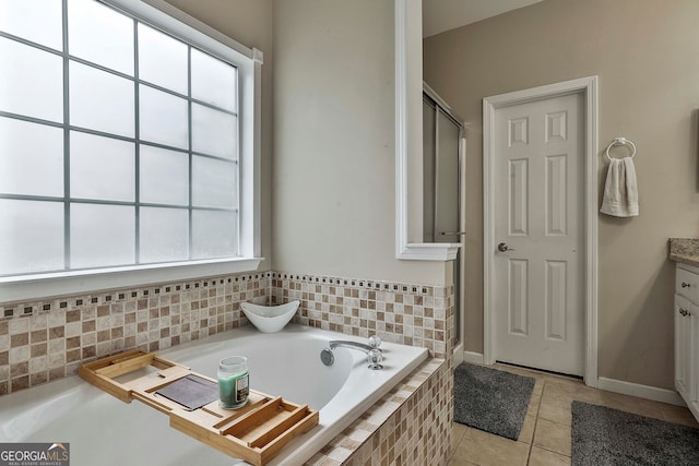 bathroom with vanity, tile patterned flooring, a healthy amount of sunlight, and a relaxing tiled tub