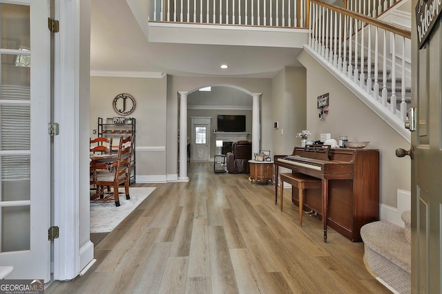 foyer entrance with ornate columns, light hardwood / wood-style flooring, and ornamental molding