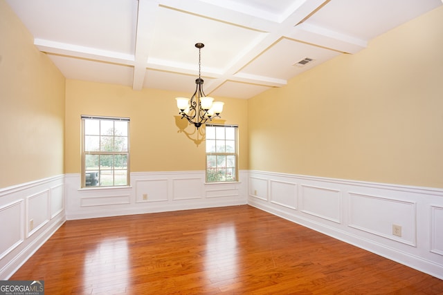 spare room featuring wood-type flooring, beam ceiling, a chandelier, and coffered ceiling