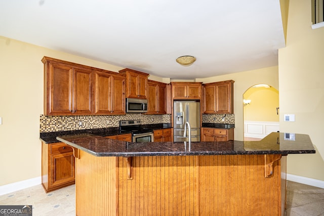 kitchen with appliances with stainless steel finishes, a large island with sink, a breakfast bar area, and backsplash