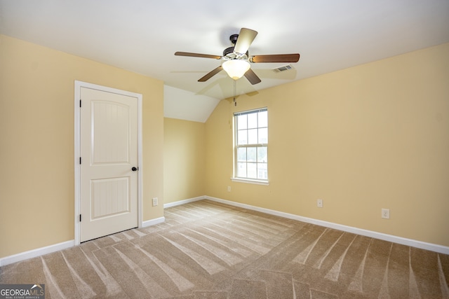 spare room with ceiling fan, light carpet, and lofted ceiling