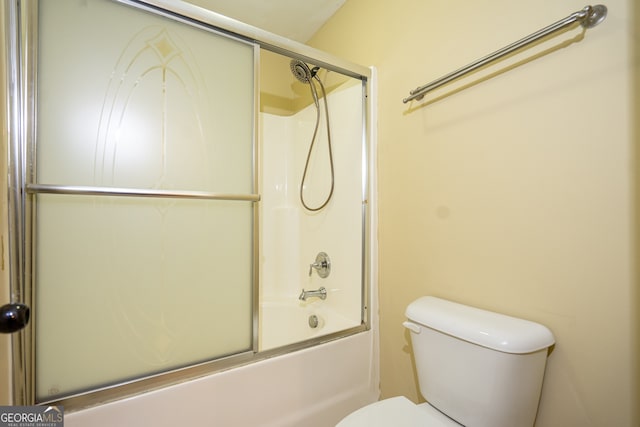 bathroom with combined bath / shower with glass door and toilet