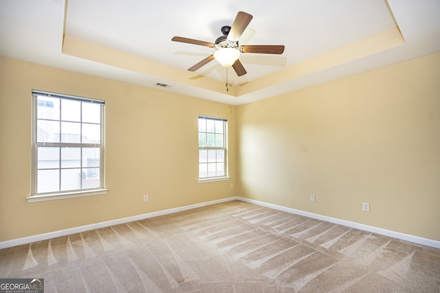 unfurnished room with a tray ceiling, carpet, and ceiling fan