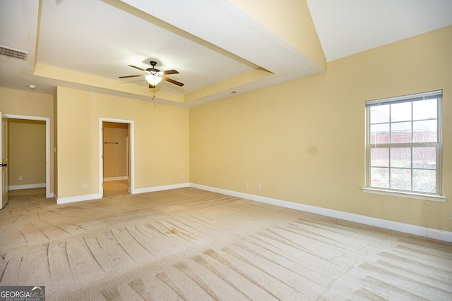 unfurnished room featuring light carpet, ceiling fan, and a raised ceiling