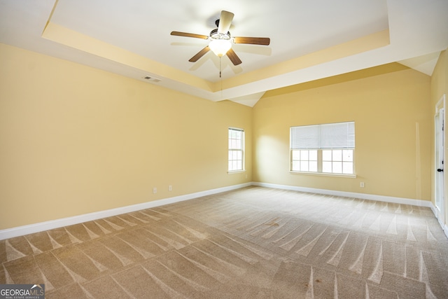 carpeted spare room featuring ceiling fan and a raised ceiling